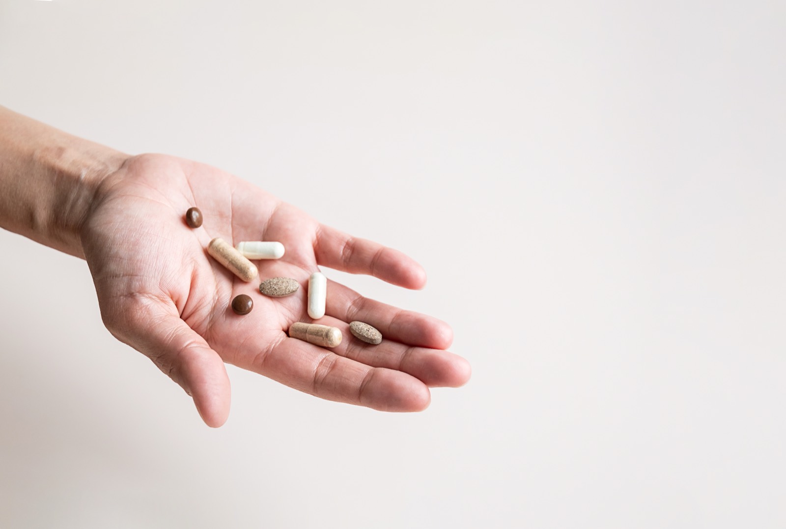 A hand holding various supplement capsules